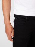 Gedetailleerde opname van de voorkant van een zwarte jeans met een wit T-shirt, close-up van de zakken.