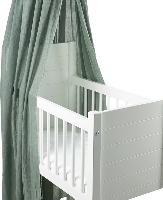 Forest green hemeltje met ruches, gedrapeerd over een wit kinderbedje.