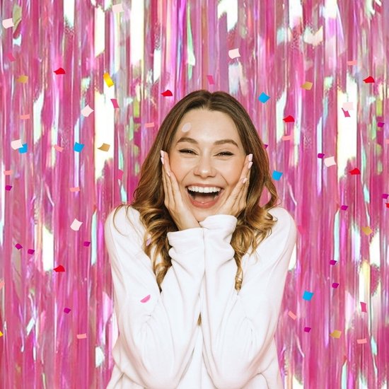 Vrolijke vrouw met handen op wangen voor glinsterende roze decoratie met confetti.