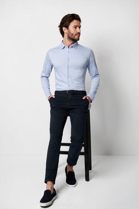 Homme assis sur une chaise, en chemise en jersey bleu clair