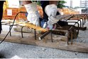 Man met veiligheidsbril en witte handschoenen gebruikt een blauwe en zilverkleurige haakse slijper van Bosch.