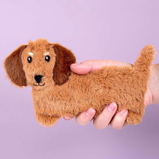 Hand houdt bruin pluche teckel warmtekussen vast, met lange oren en staart.