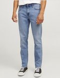 Man in lichtblauwe jeans, wit T-shirt en zwarte sneakers met witte zolen.