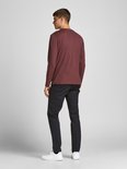 Man met bordeauxrode longsleeve en zwarte chino.