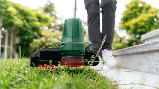 Close-up van de snijkop van een Bosch grastrimmer die gras trimt, met indicatie van snijhoogte.