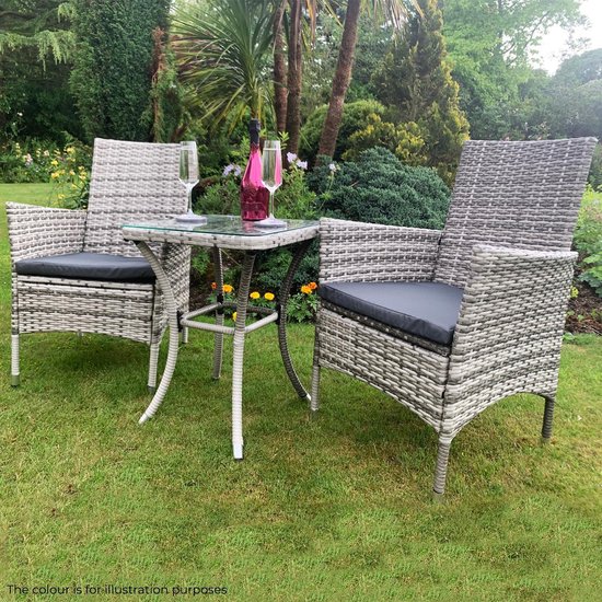 Grijze rotan stoelen en tafel in een tuinsetting, met fles en glazen.
