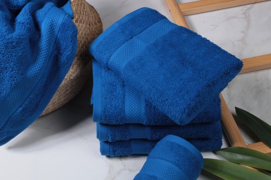 Een stapel klassiek blauwe handdoeken in een rieten mand, naast een houten ladder.