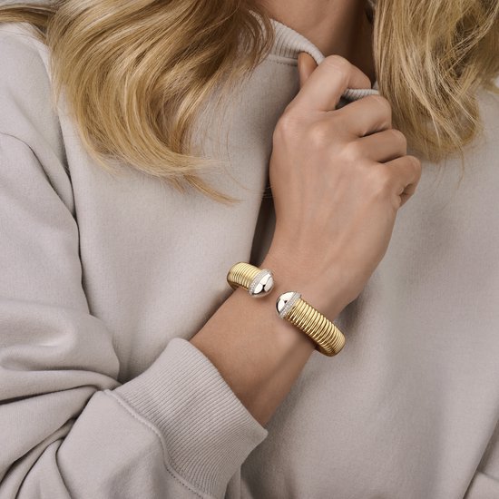 Model draagt een gouden Tubogas armband met zilverkleurige, zirkoniabijlbelde uiteinden.