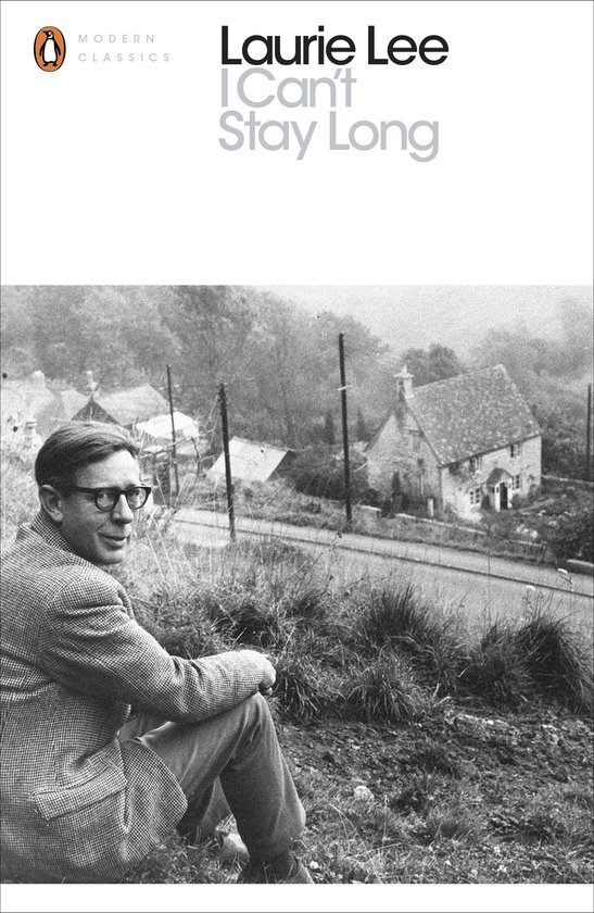 Laurie Lee en veste en tweed, assis sur une colline surplombant un village.