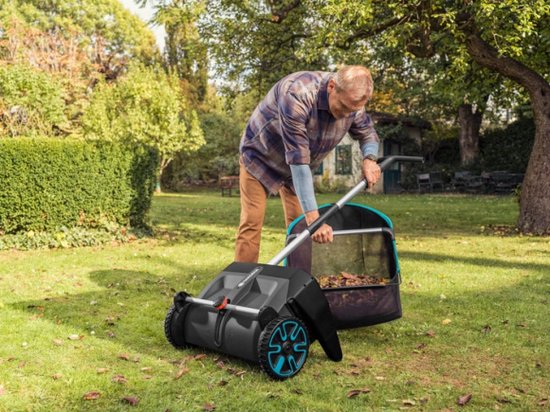 Een man bukt zich om bladeren te verzamelen met de Gardena bladverzamelaar op een grasveld.