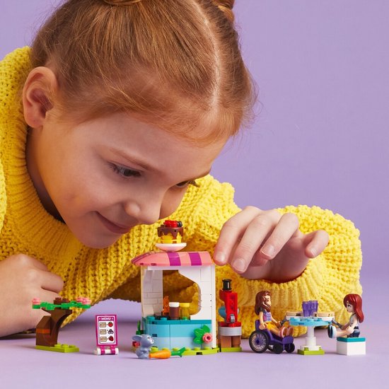 Fille aux couettes rousses et pull jaune regardant La Crêperie LEGO Friends.