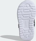 Onderkant van witte kindersneaker met zwart Adidas-logo en groeven.