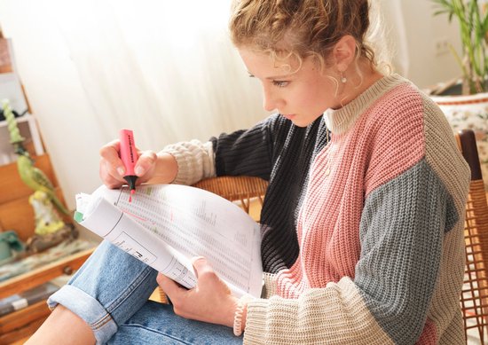 Vrouw met krullend haar markeert documenten met een felrode STABILO BOSS Original stift.