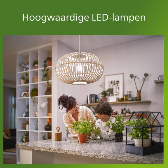 Een vrouw en een kind kijken naar planten in een keuken met een ronde lampenkap aan het plafond.