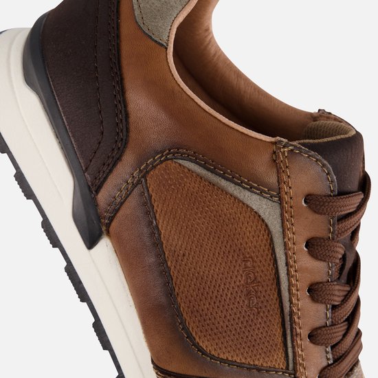Close-up van de bruine leren Rieker sneaker met contrasterende panelen en stiksels.