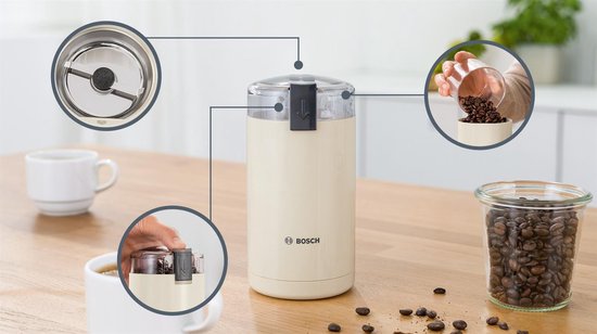 Crème elektrische koffiemolen van Bosch op een houten tafel, met illustraties van de werking.