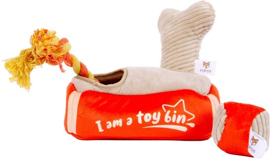 Rode en beige pluche speelgoedmand met de tekst "I am a toy bin", met een bot en touw erin, op witte achtergrond.