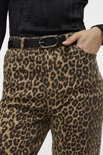 Close-up van wijde jeans met luipaardprint en zwarte riem.