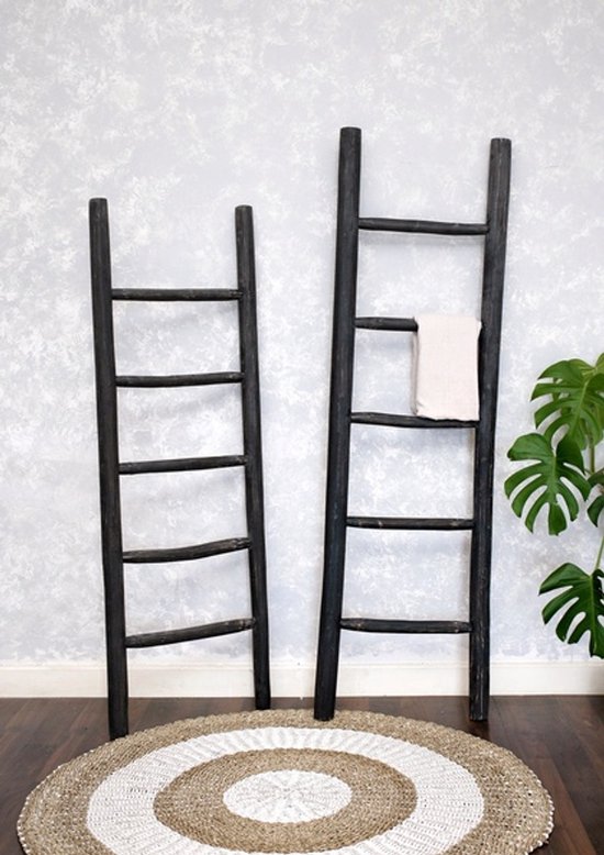 Twee zwarte houten decoratieve ladders, waarvan de grootste een beige geruite handdoek draagt.