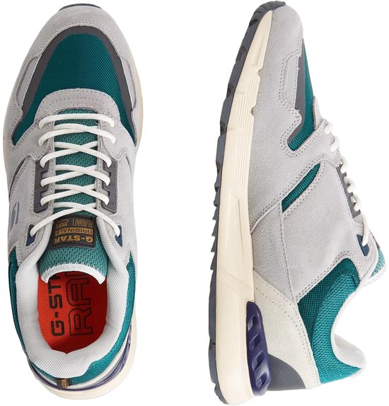 Lichtgrijze G-Star sneakers met teal-groene accenten. De sneakers hebben witte veters en een oranje binnenzool.