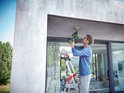 Man op ladder monteert met groene Bosch boorhamer aan plafond.