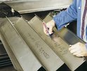 Een hand met een blauwe Edding marker schrijft op metalen platen met tekst.