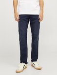 Blauwe jeans gedragen door een man met een wit T-shirt en witte sneakers.