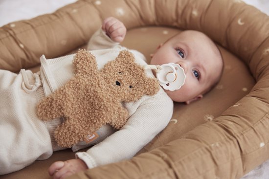 Baby in slaapnest met teddybeer speenkoord.