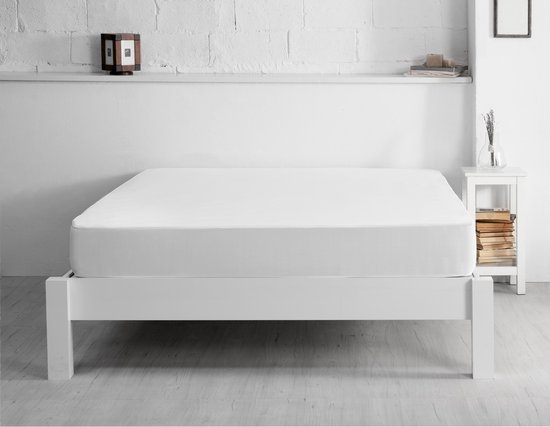 Een witte matrasbeschermer ligt op een wit houten ledikant in een slaapkamer.
