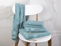 Serviettes bleu clair de différentes tailles sur une chaise blanche. Une serviette est suspendue au dossier.