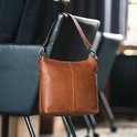 Een cognac kleurige leren schoudertas van The Chesterfield Brand, gedragen door een model.