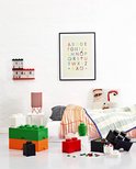 Een slaapkamer met een bed, kleding en LEGO opbergdozen in verschillende kleuren.