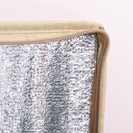 Close-up van de zilverkleurige, aluminium binnenzijde van een beige koeltas met rits.