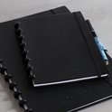 Twee zwarte Correctbooks op elkaar, een met een pen erin. Close-up van de spiraalbinding.