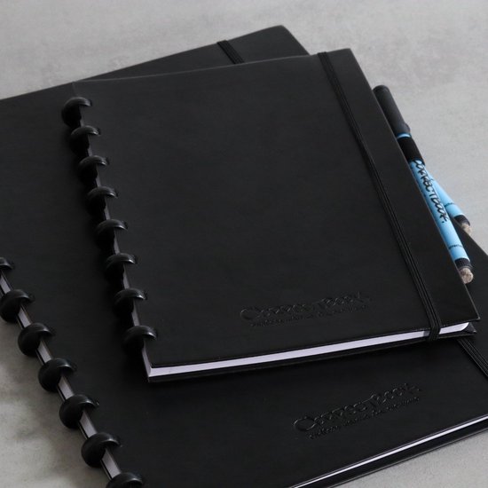 Twee zwarte Correctbooks op elkaar, een met een pen erin. Close-up van de spiraalbinding.