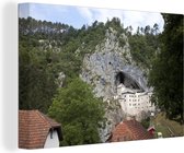 Canvas Schilderij Grad Predjama met uitzicht op het landschap in Slovenië - 60x40 cm - Wanddecoratie