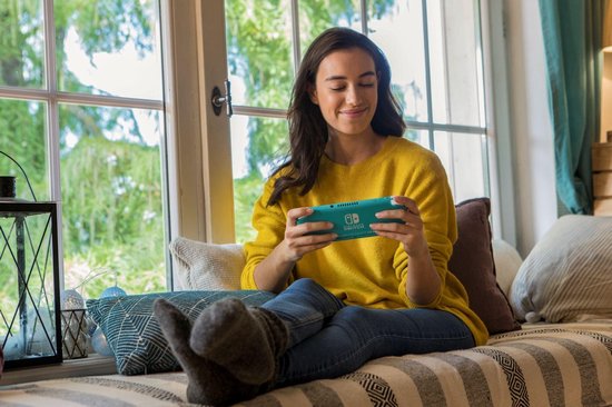 Een vrouw in een gele trui speelt op een turkoois Nintendo Switch-spel.