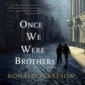 Boekcover van 'Once We Were Brothers'. Twee mannen lopen over een geplaveide straat in een historische stad. De titel 'ONCE WE WERE BROTHERS' staat centraal.