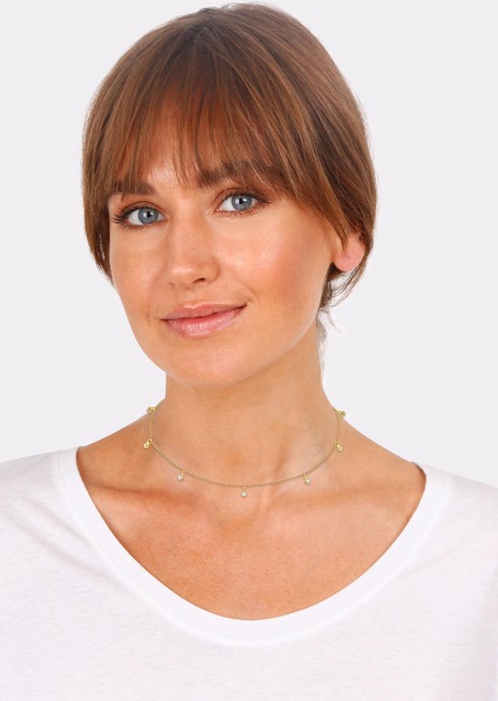 Model draagt gouden ketting met zirkonia kristallen en vlinder bedeltjes.