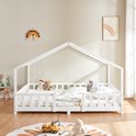 Lit maison blanc avec barreaux, décoré de linge de lit et de peluches.
