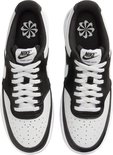 Achterkant van een paar witte en zwarte Nike Court Vision Low sneakers, met "NIKE" in witte letters op de hielen.