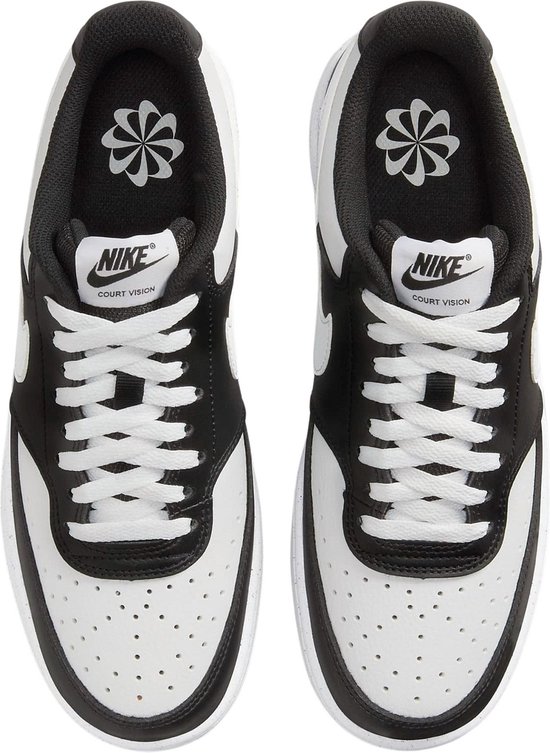 Achterkant van een paar witte en zwarte Nike Court Vision Low sneakers, met "NIKE" in witte letters op de hielen.