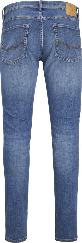 Achterkant van een man in een grijs t-shirt en blauwe jeans, staand met de handen in de zakken.