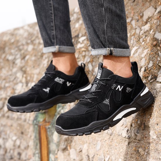 Zwarte NezR werksneakers met witte accenten, gedragen door een man.