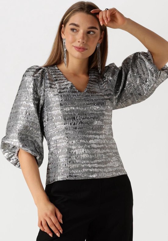 Model draagt zilveren blouse met pofmouwen en V-hals, met horizontale textuur.