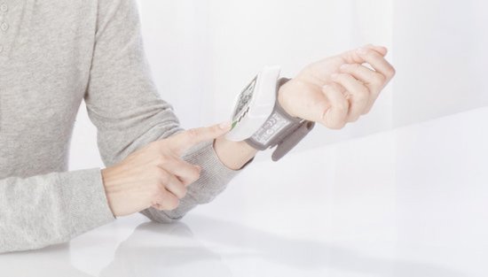 Grijze polsband van een Medisana bloeddrukmeter om de pols van een persoon.