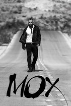 Een man met een baard en een spijkerjasje loopt over een lege weg. De tekst 'MOX' staat op de voorgrond.