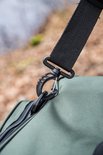Zwarte clip aan de schouderband van een groene tas, close-up.
