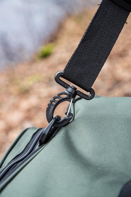 Zwarte clip aan de schouderband van een groene tas, close-up.