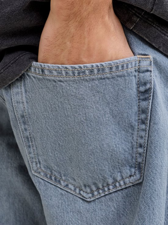 Close-up van de achterzak van een blauwe jeans, een hand steekt erin.